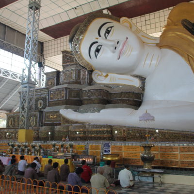 El buddha reclinado de Shwe Tha Lyaung con algunos fieles rezándole