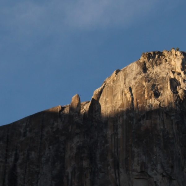 Zoom donde se ve un pequeño punto (el escalador) en el aire entre la roca "suelta" y la cima