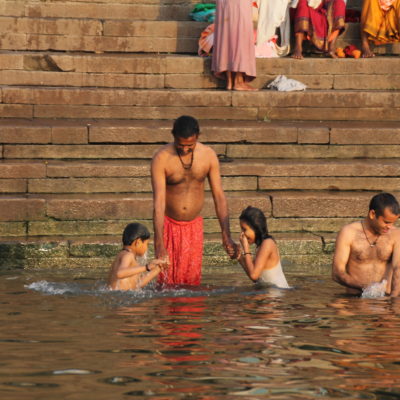 Un padre sujeta a sus niños mientras éstos se sumergen en las aguas del Ganges
