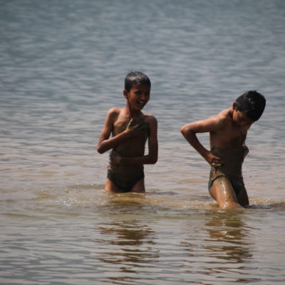 Niños jugando con el barro del fondo del lago